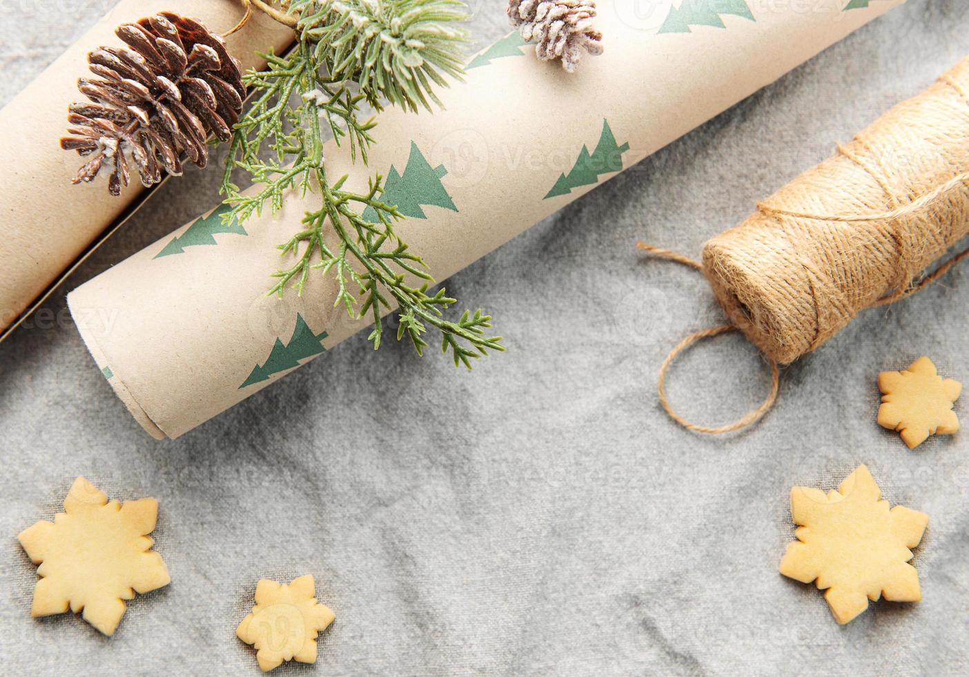 papel de embrulho com um galho de pinheiro e biscoitos de natal em um fundo têxtil foto