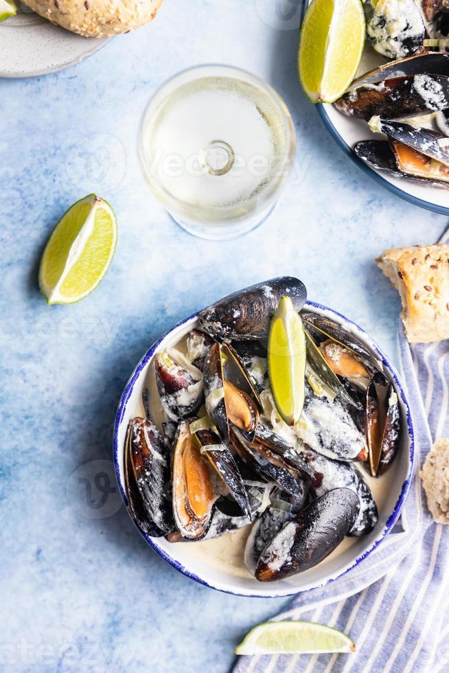 mexilhões azuis em molho cremoso de vinho branco servido com limão e pão. mexilhões cozidos no vinho, alho francês e queijo azul. frutos do mar. foto