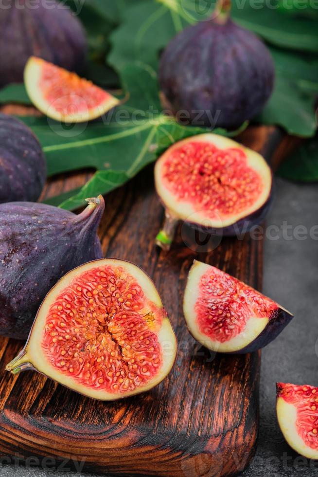 figos cortados em fatias em uma placa de corte de madeira close-up, foco seletivo. frutas maduras sazonais de moldura vertical, dieta mediterrânea, ideia para plano de fundo foto