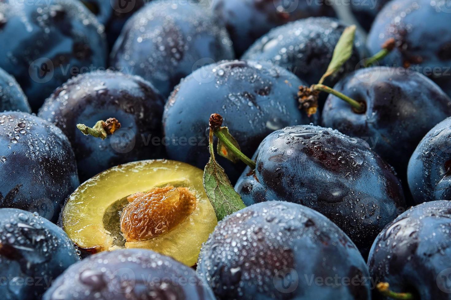 metades de ameixas e ameixas, fundo de frutas orgânicas frescas em gotas de água, close-up. foco seletivo, profundidade de campo lindas ameixas maduras, colheita de frutas no outono, produtos ecológicos foto