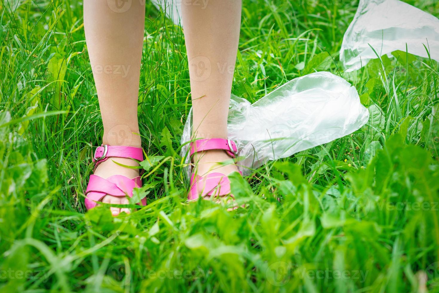 lixo de sacos de plástico com pés de crianças na grama verde foto