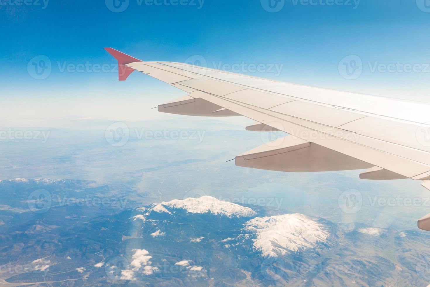 asa de aeronave nas nuvens, voa no fundo das montanhas foto