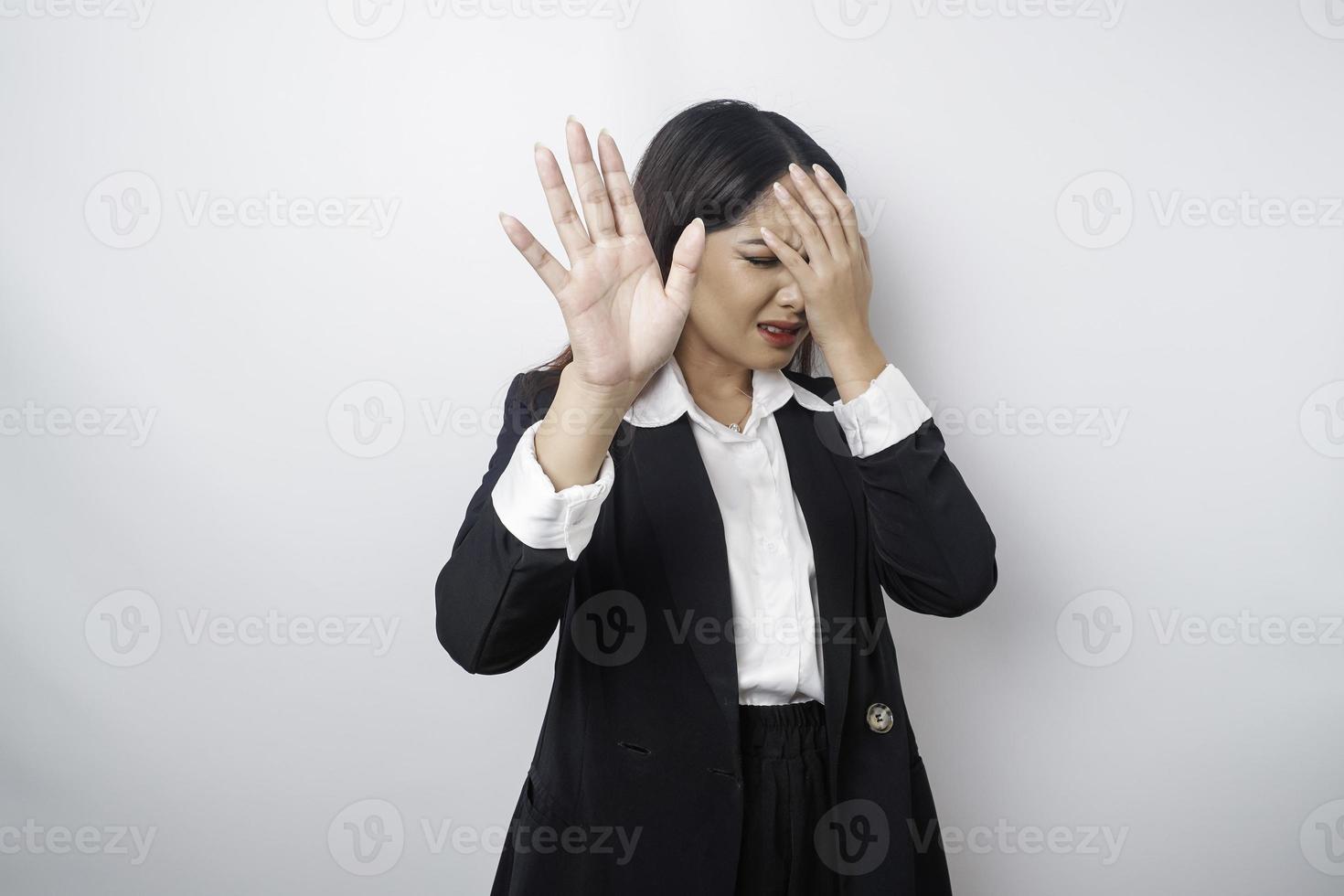 jovem mulher de negócios asiáticos isolada no fundo branco, parece deprimida, rosto coberto por dedos assustados e nervosos. foto