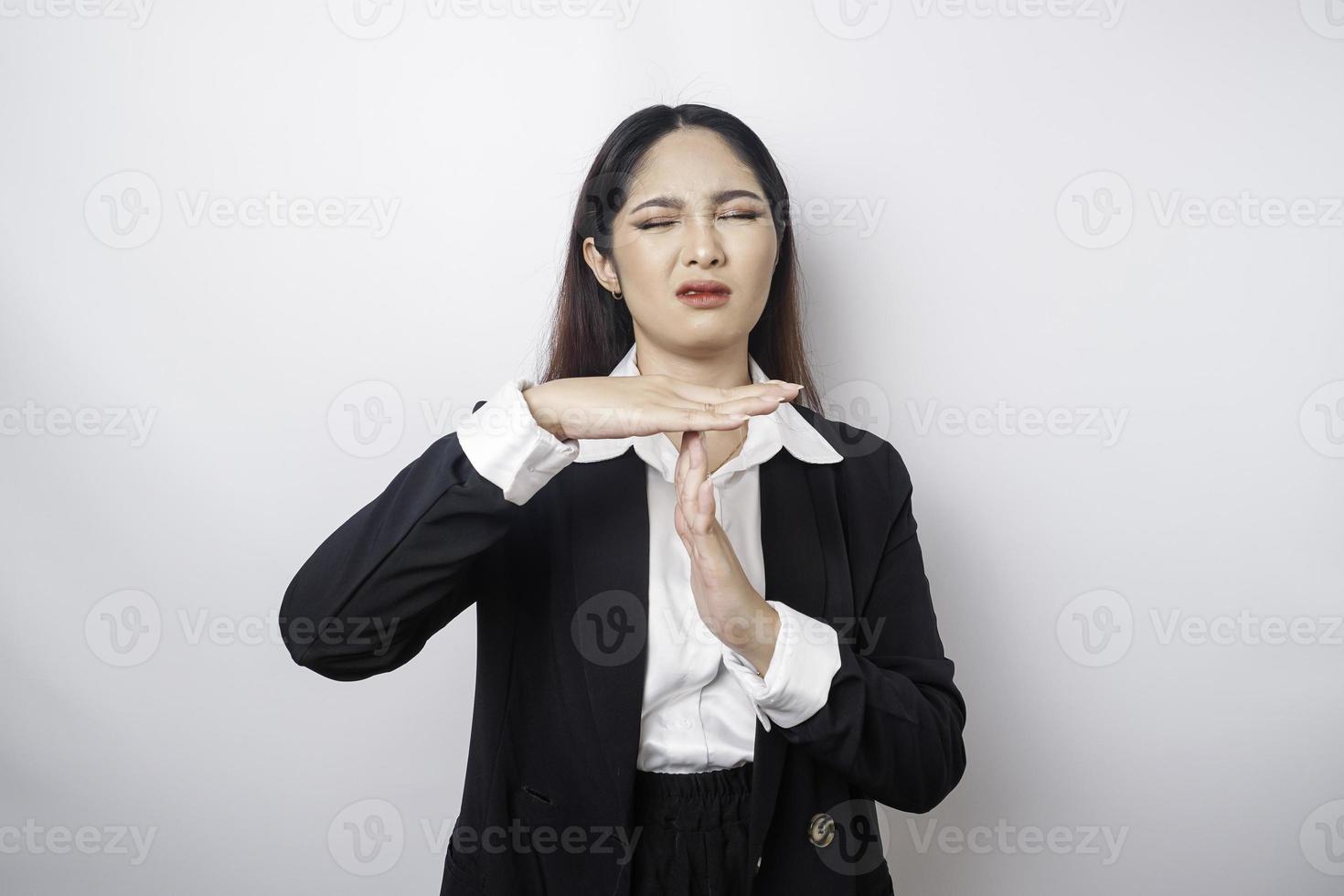 empresária asiática hispânica vestindo terno preto fazendo gesto de tempo com as mãos, rosto sério e frustrado foto