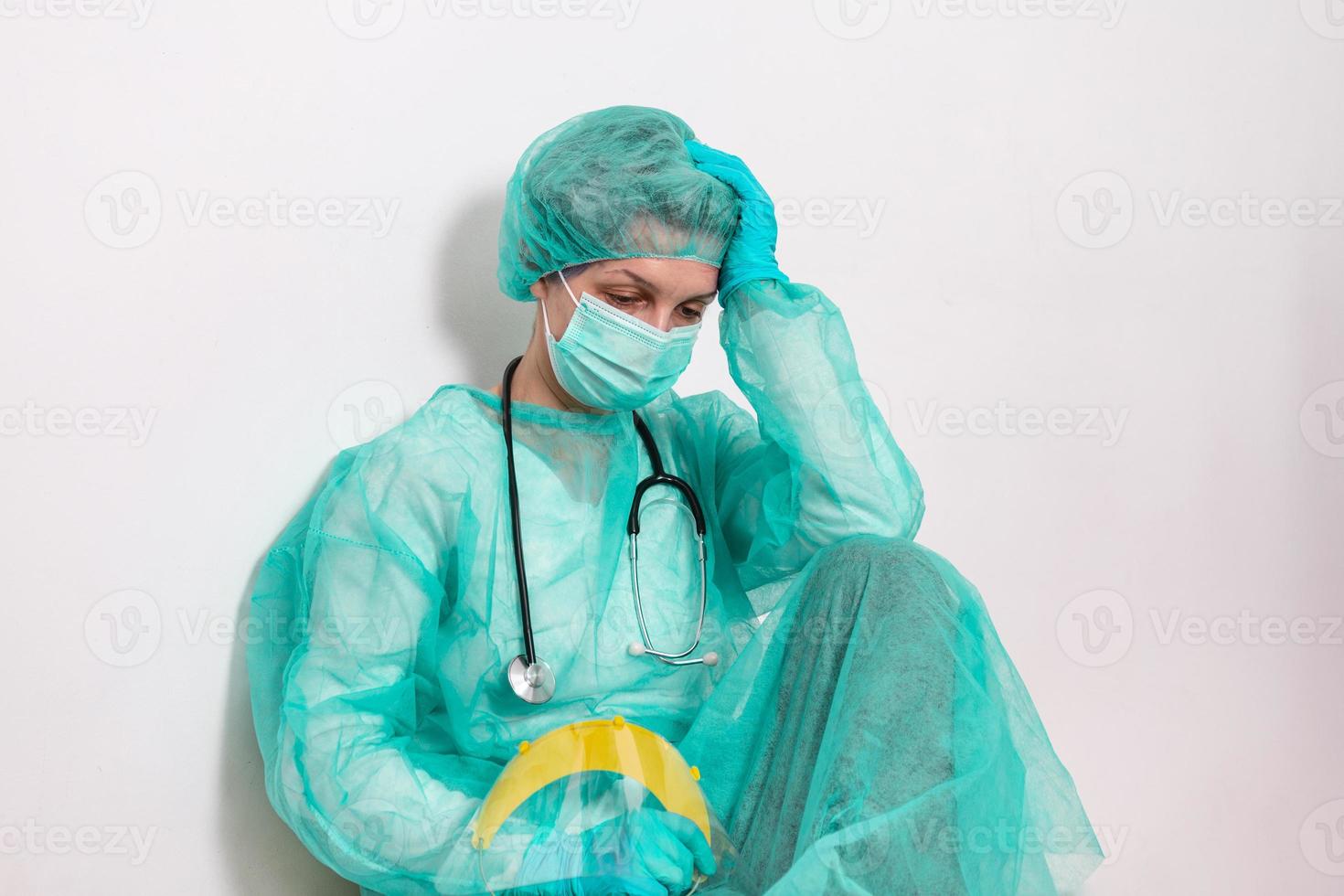 conceito de coronavírus. covid19. jovem médica em traje de proteção uniforme, máscara facial e luvas de borracha, antes do exame do paciente, sentindo-se exausta e preocupada. médicos são heróis. foto