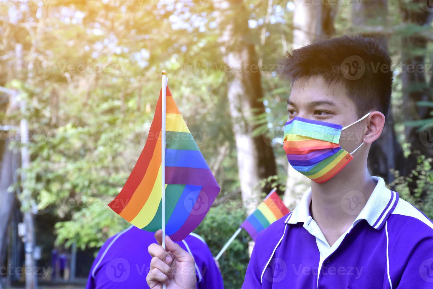 retrato de menino asiático segura a bandeira do arco-íris, símbolo lgbt, nas mãos enquanto se junta à sua atividade lgbt na escola, conceito para a celebração da comunidade lgbt no mês do orgulho, junho de 2023, em todo o mundo. foto