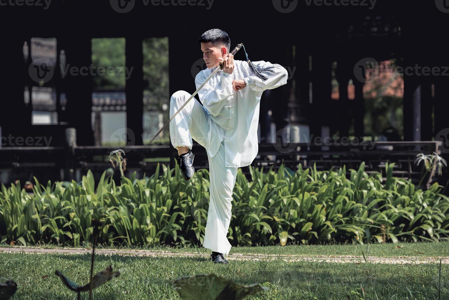 jovem praticando espada tradicional de tai chi, tai ji no parque para o conceito saudável e tradicional de artes marciais chinesas em fundo natural. foto