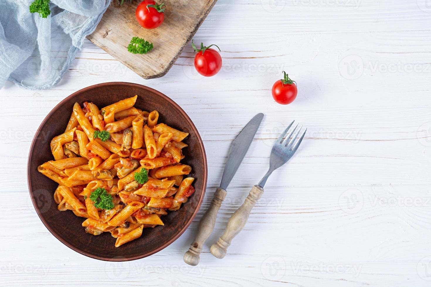 macarrão penne ao molho marinara com mexilhões, cebola e salsa. penne de massa italiana clássica. vista do topo foto