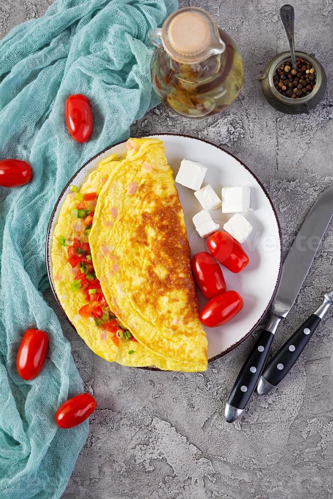 omelete frito com carne, tomate, cebola e ervas. delicioso café da manhã com ovos mexidos. vista do topo foto