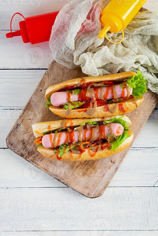 delicioso cachorro-quente com ketchup e mostarda em fundo de madeira. comida de rua foto