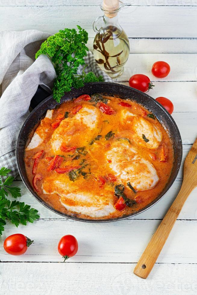 ensopado de peito de frango com tomate, pimenta e espinafre na panela foto