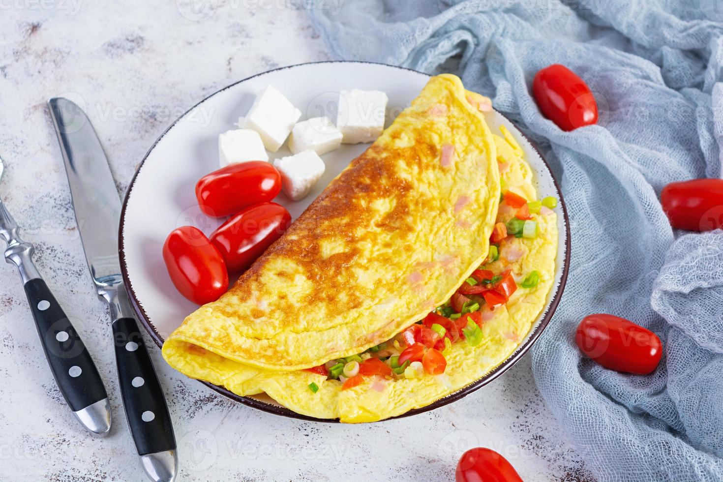 omelete frito com carne, tomate, cebola e ervas. delicioso café da manhã com ovos mexidos foto
