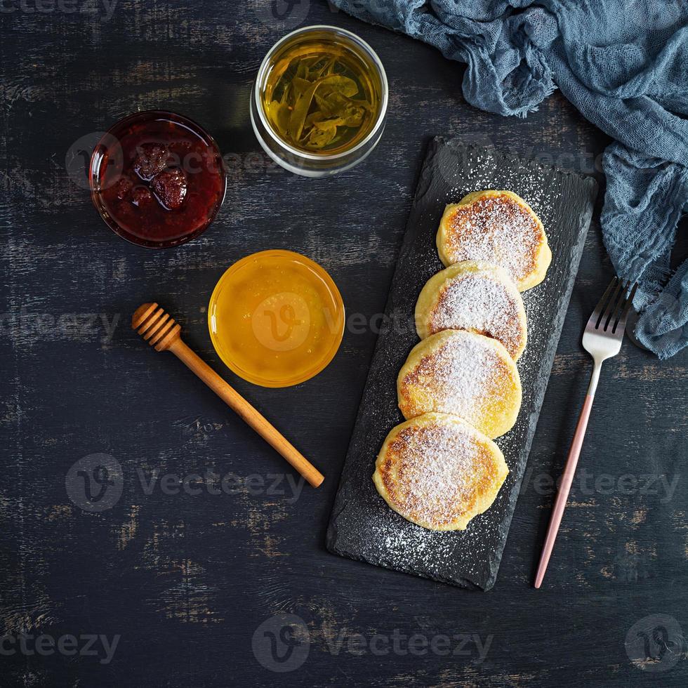 delicioso syrniki caseiro com geleia de morango e mel. prato tradicional russo syrniki foto