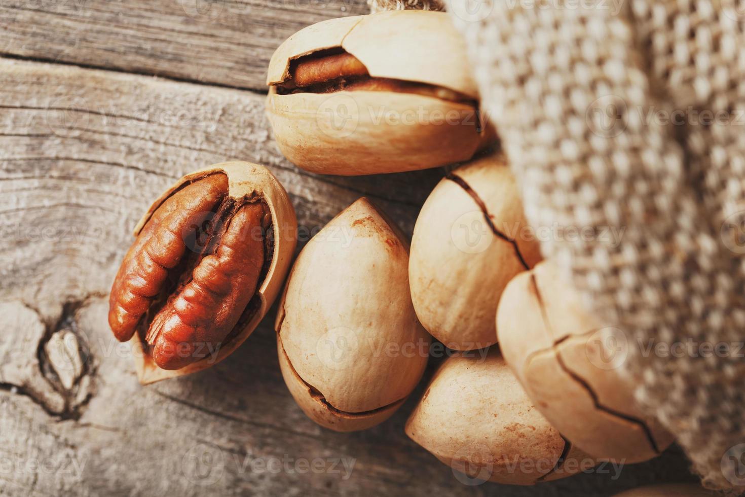 pecans derramam de um saco em uma mesa de madeira, close-up. descascado, em uma casca. baixo contraste foto