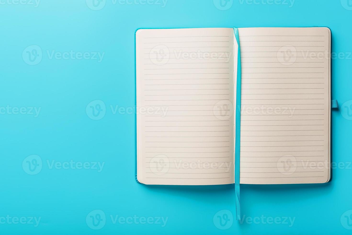 caderno aberto, um livro com páginas em branco e em branco sobre um fundo azul, vista superior. foto