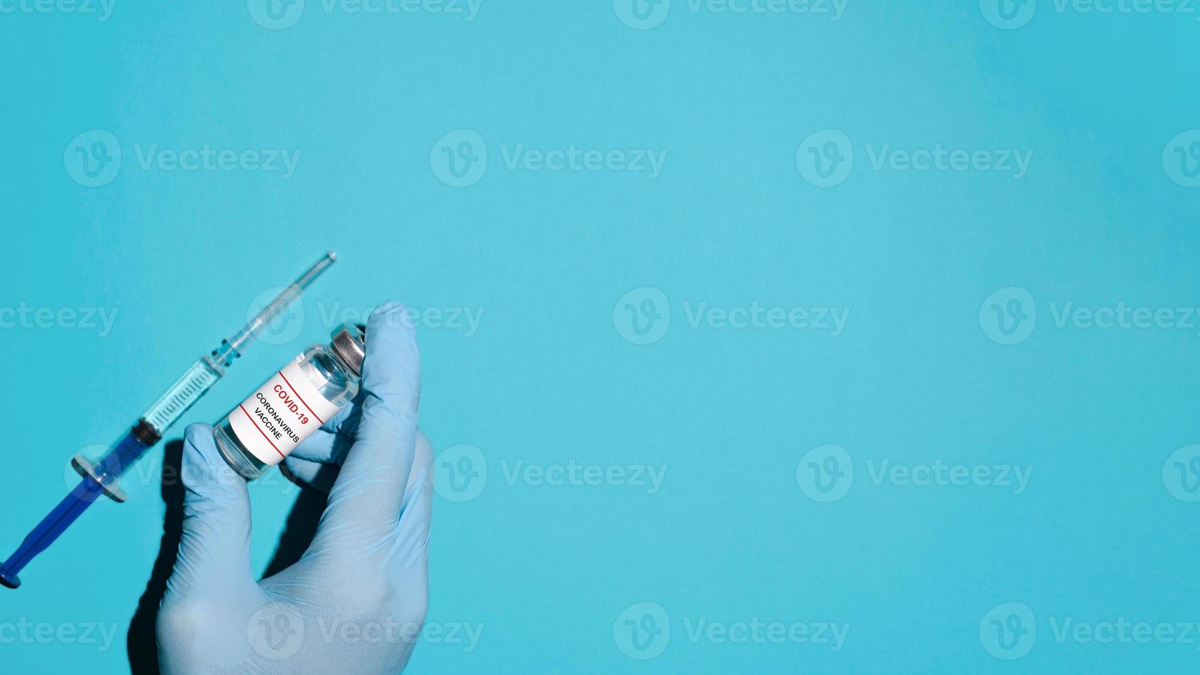 mão do médico em uma luva segurando o frasco com vacina e seringa, vista superior. bandeira, copie o espaço foto
