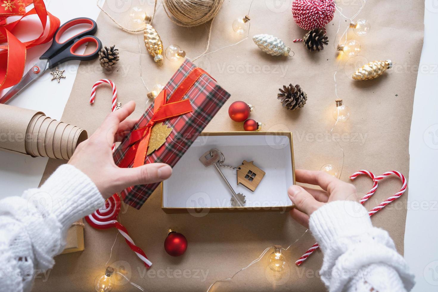 chave para casa com chaveiro em casa aconchegante em caixa de presente com embalagem de decoração de natal. embalar presente para o ano novo, natal. construção, projeto, mudança para casa nova, hipoteca, aluguel, compra de imóveis foto