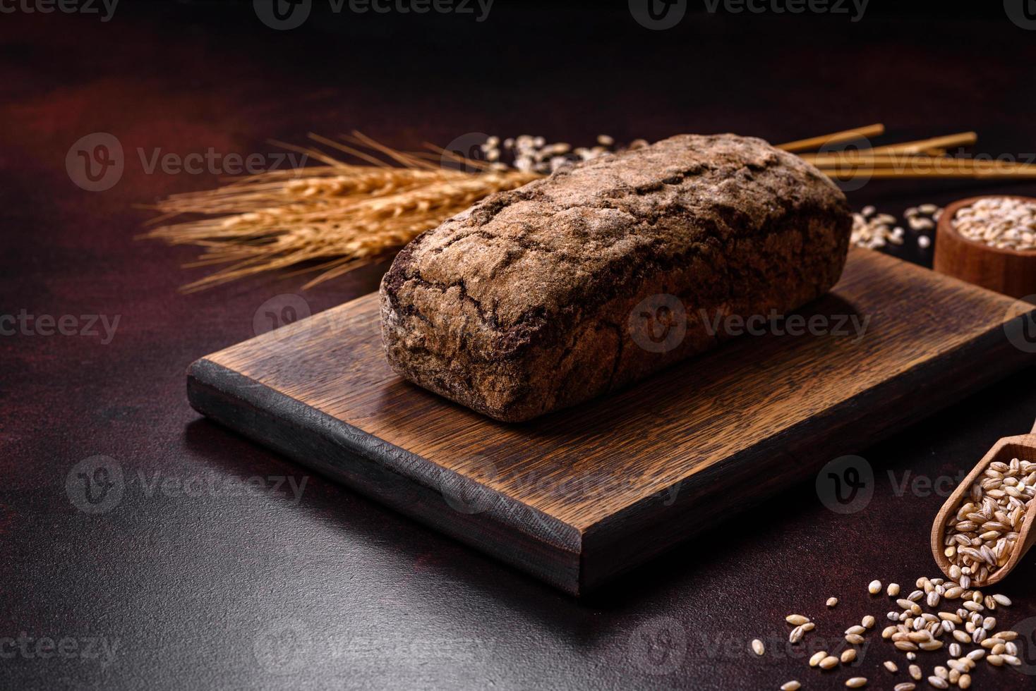 um pedaço de pão integral com grãos de cereais em uma tábua de madeira foto