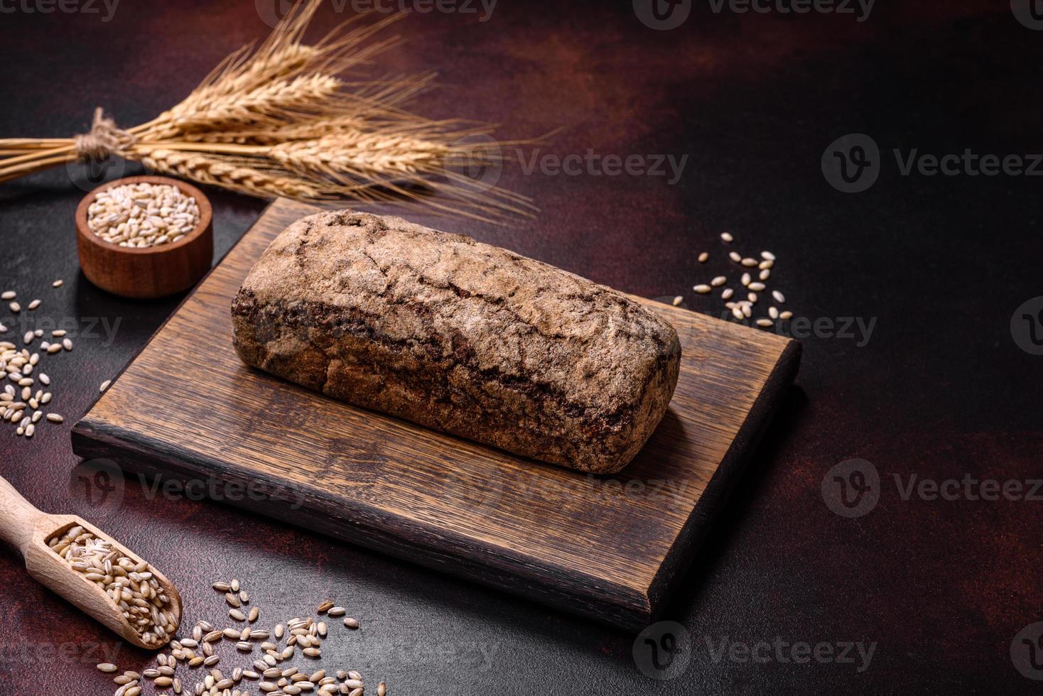 um pedaço de pão integral com grãos de cereais em uma tábua de madeira foto