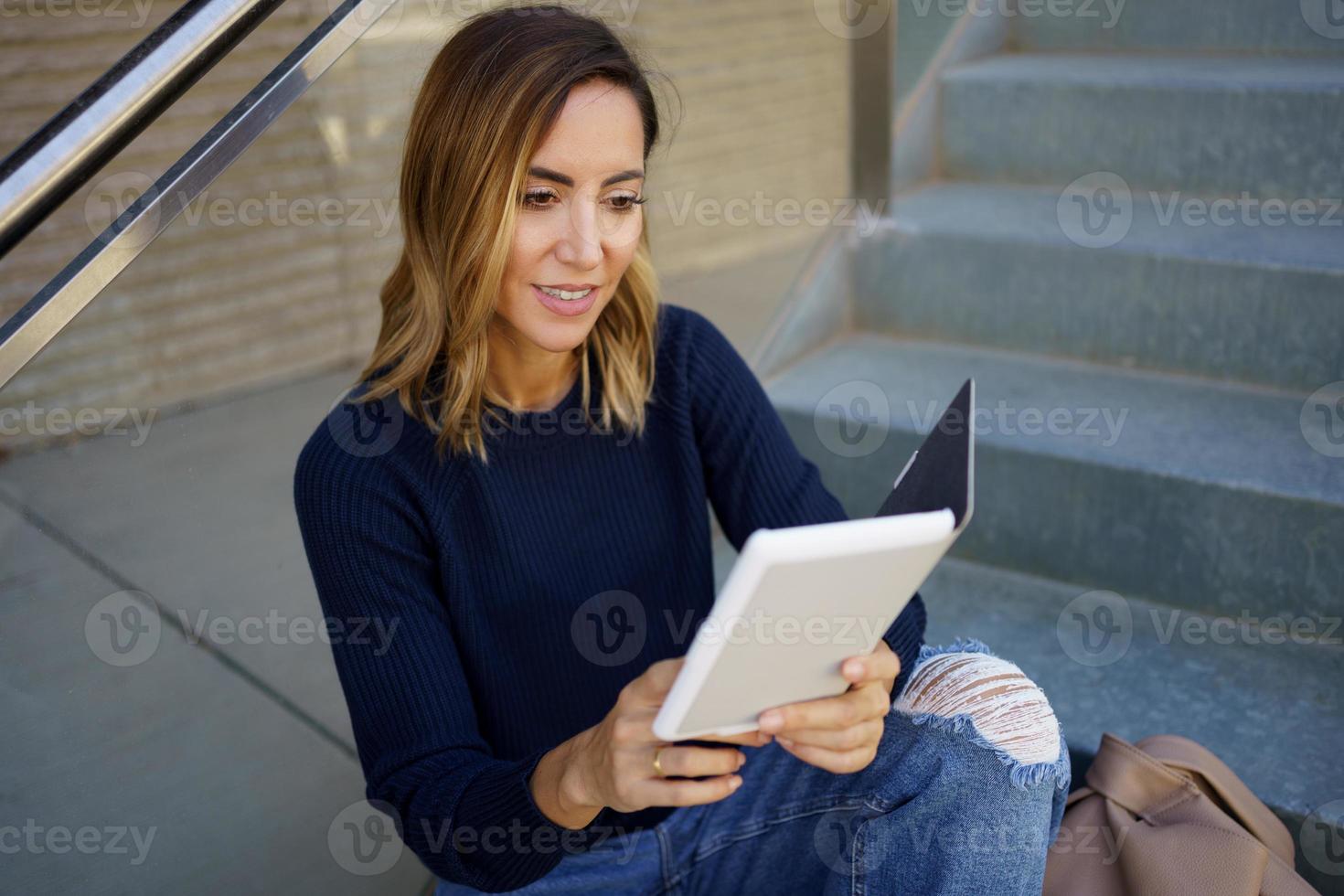 mulher positiva sorrindo e lendo e-book foto