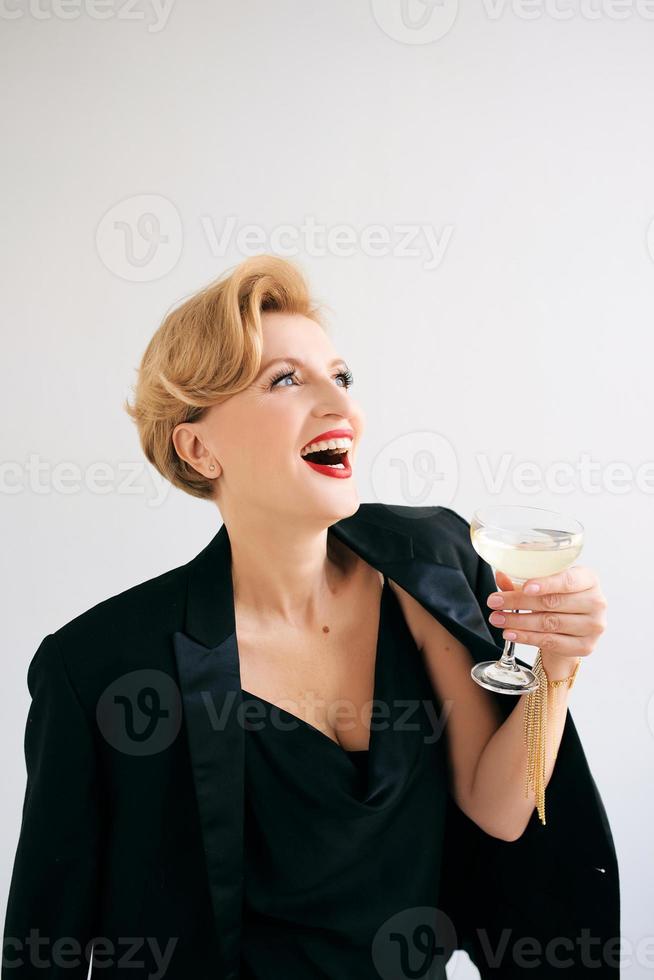 rindo caucasiana madura elegante elegante mulher de smoking com copo de vinho espumante. festa, celebração, conceito anti-idade foto