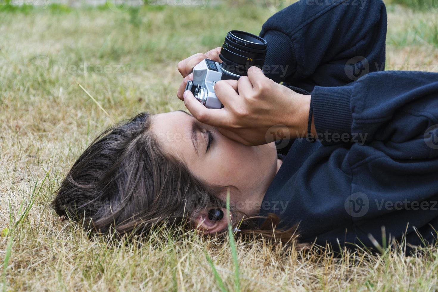 linda garota adolescente com uma câmera, uma garota tirando fotos em uma câmera vintage retrô na grama do parque, um conceito de hobby
