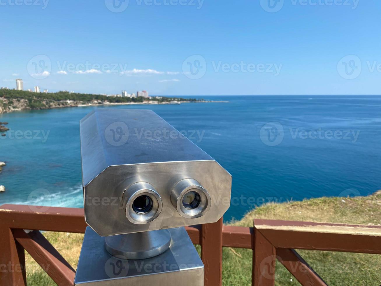 uma plataforma de observação no aterro, equipada com um binóculo de visualização estacionário com vista para o mar e o porto marítimo foto