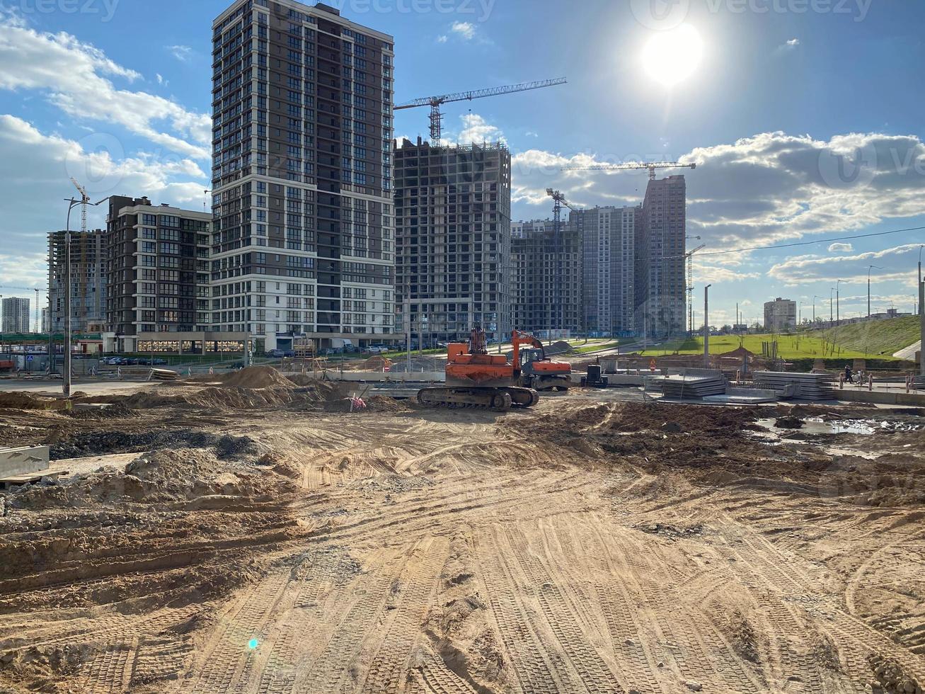 um grande canteiro de novas casas altas de edifícios monolíticos de concreto com guindastes e equipamentos de construção durante a reparação de novos edifícios em uma grande cidade densamente povoada foto