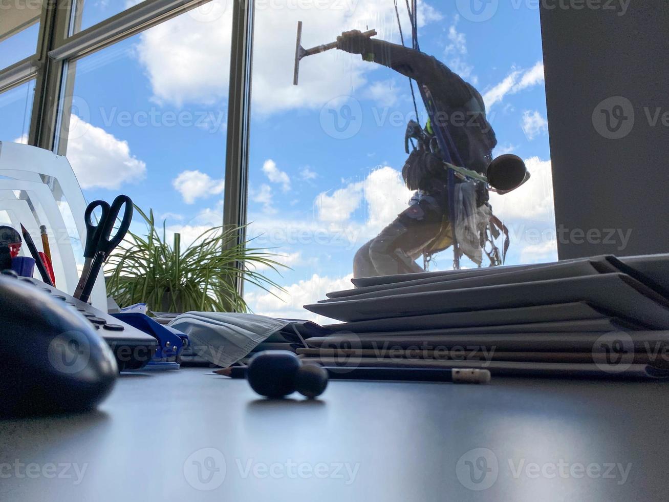 alpinista industrial pendurado no varal e lava janelas, edifício moderno de fachada de vidro foto