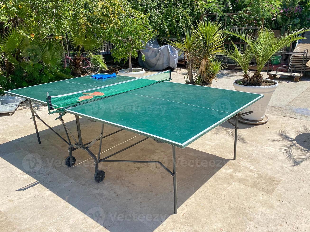 duas raquetes de tênis de mesa ou ping pong e bolas em uma mesa verde com rede foto