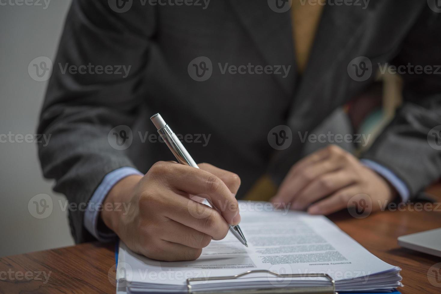 empresário assina documentos com uma caneta fazendo a assinatura na mesa. foto