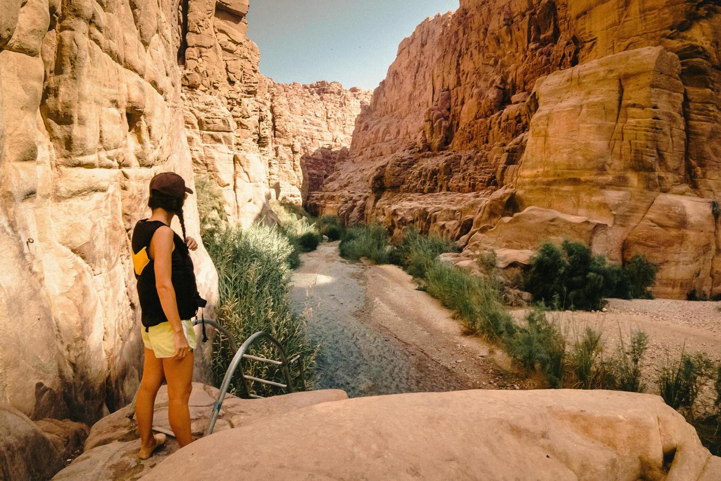 turista feminina desfruta do desfiladeiro do rio de wadi mujib com incríveis cores claras douradas. wadi mujib está localizado na área do mar morto na jordânia foto