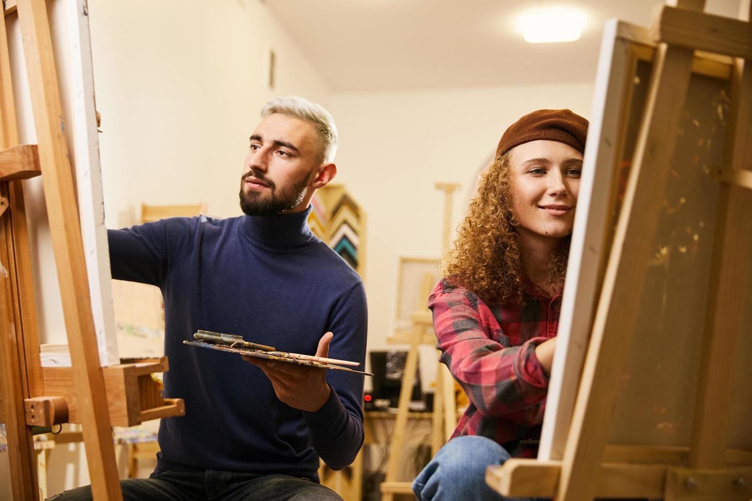 homem e mulher desenham pinturas em cavaletes foto