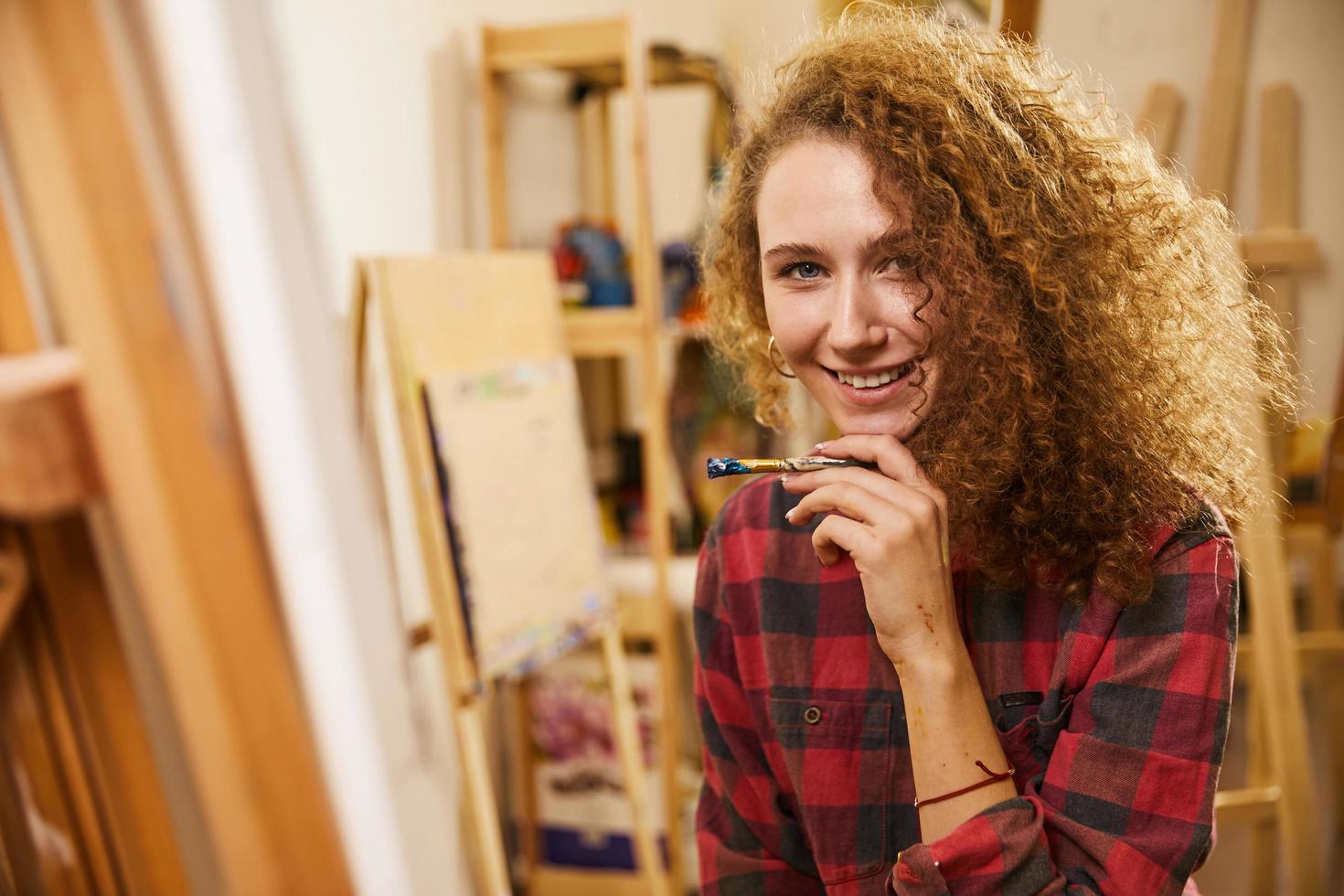 menina bonita segurando uma escova perto do queixo e sorrindo foto