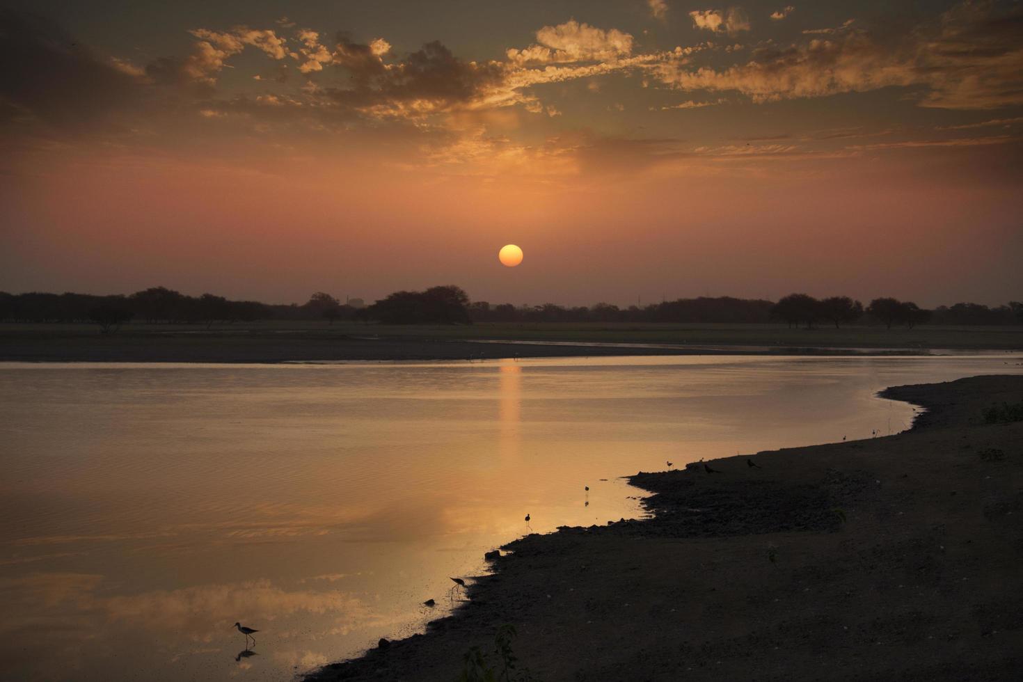 pôr do sol sobre um corpo de água foto