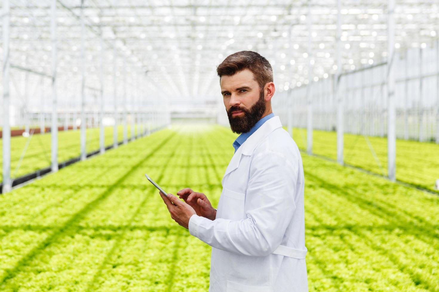 pesquisador masculino estudando plantas com um tablet foto