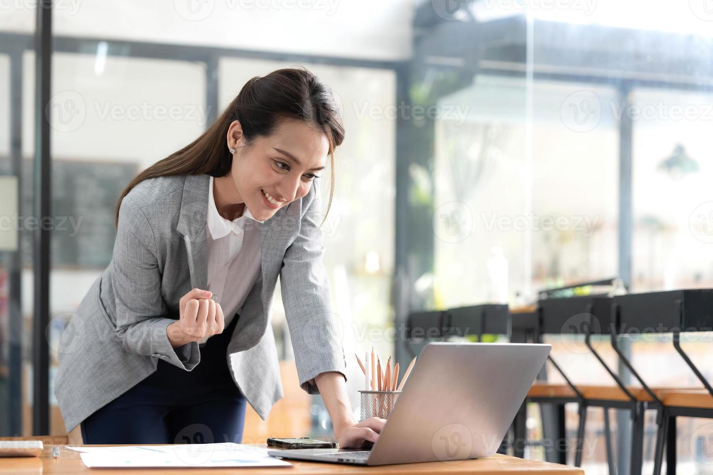 mulher asiática feliz animada olhando para a tela do telefone, comemorando uma vitória online, jovem mulher asiática muito feliz gritando de alegria, isolada sobre um fundo branco desfocado foto