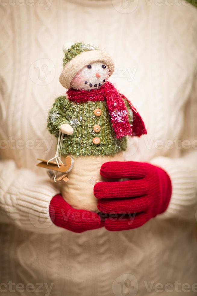 mulher vestindo luvas vermelhas sazonais segurando boneco de neve de natal foto
