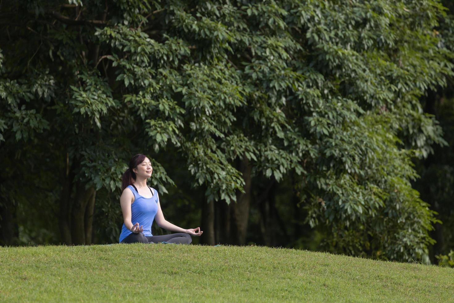 jovem mulher asiática em traje de ioga praticando relaxantemente meditação na floresta para alcançar a felicidade da paz interior sabedoria para exercícios respiratórios, mente saudável e conceito de alma foto