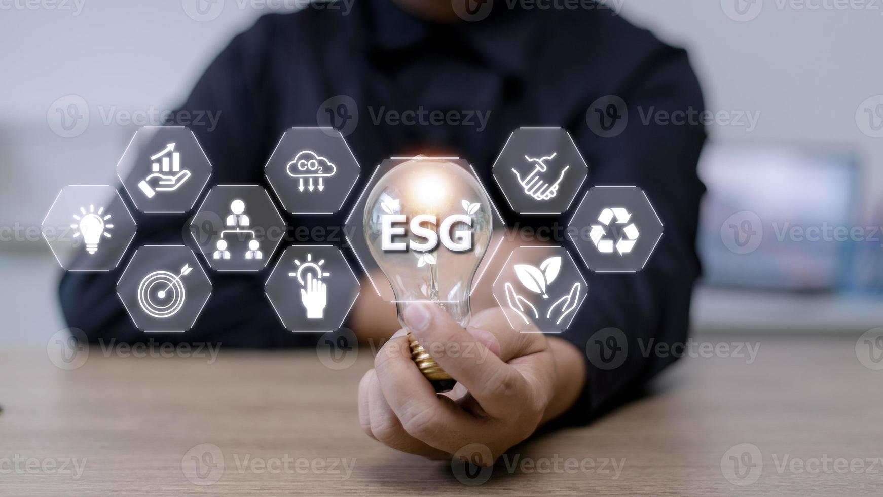 mão de empresário segurando a lâmpada com ícone esg na tela virtual, conceito de governança corporativa, social e ambiental esg foto