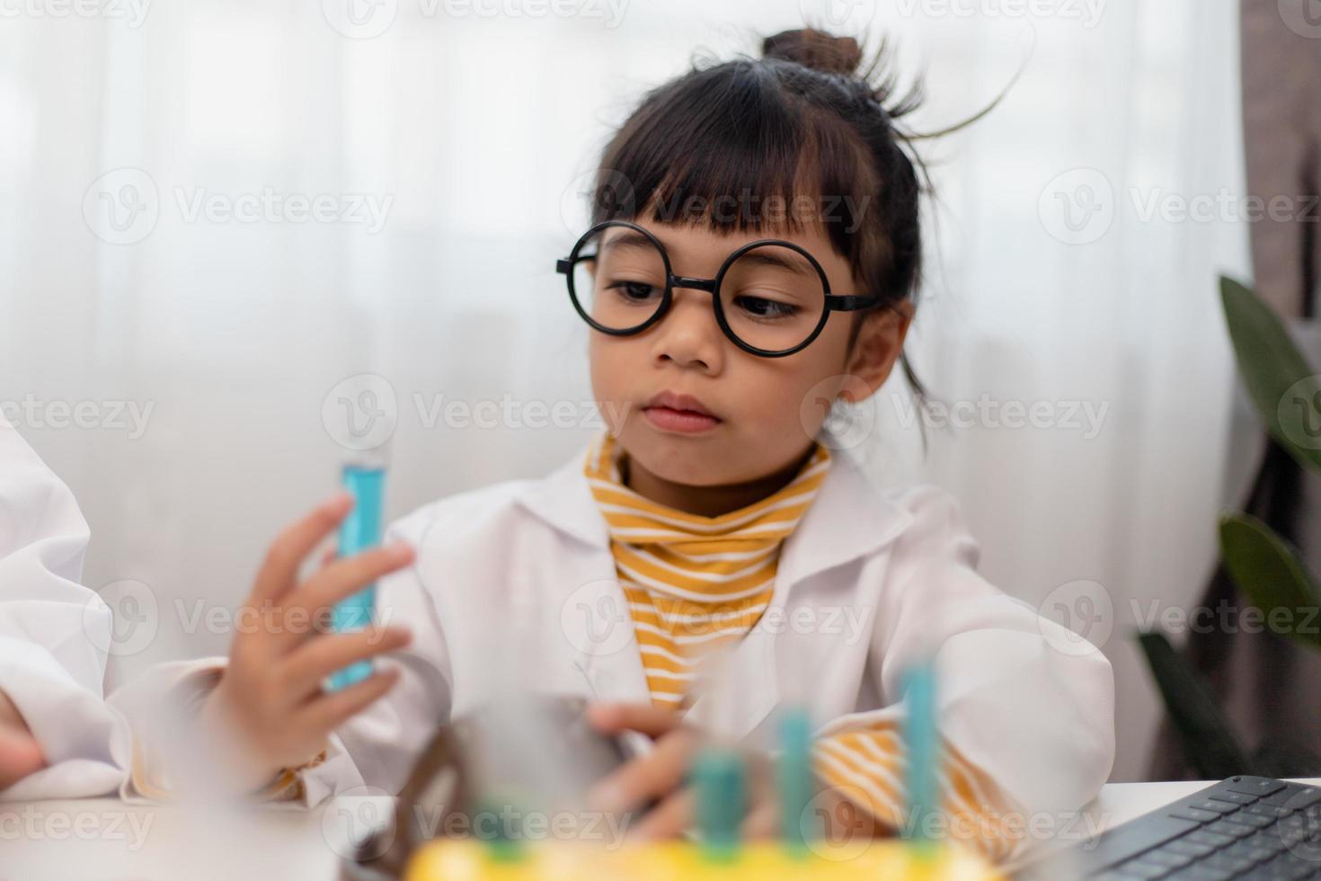 menina asiática medindo a temperatura da água quente e fria para uma aula on-line experimental de ciências fácil foto