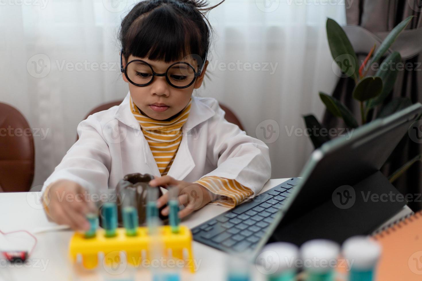 menina asiática medindo a temperatura da água quente e fria para uma aula on-line experimental de ciências fácil foto