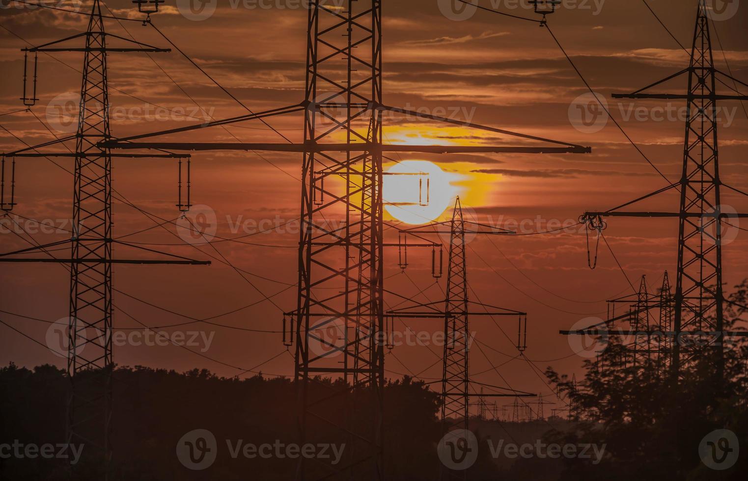 postes de energia na frente do sol poente foto
