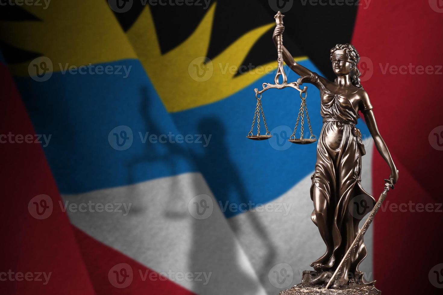 Bandeira de Antígua e Barbuda com a estátua da Justiça e balança judicial em quarto escuro. conceito de julgamento e punição foto