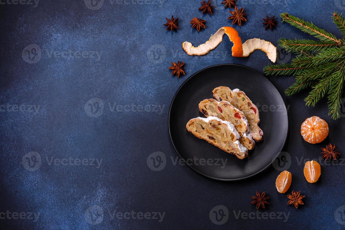 deliciosa torta festiva de ano novo com frutas cristalizadas, maçapão e nozes em um fundo escuro de concreto foto