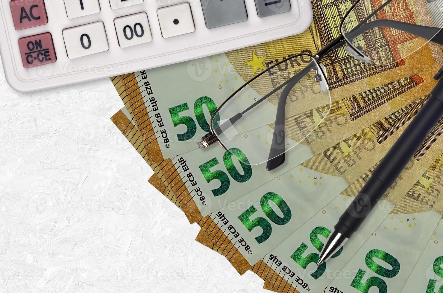 Ventilador de notas de 50 euros e calculadora com óculos e caneta. empréstimo comercial ou conceito de temporada de pagamento de impostos foto