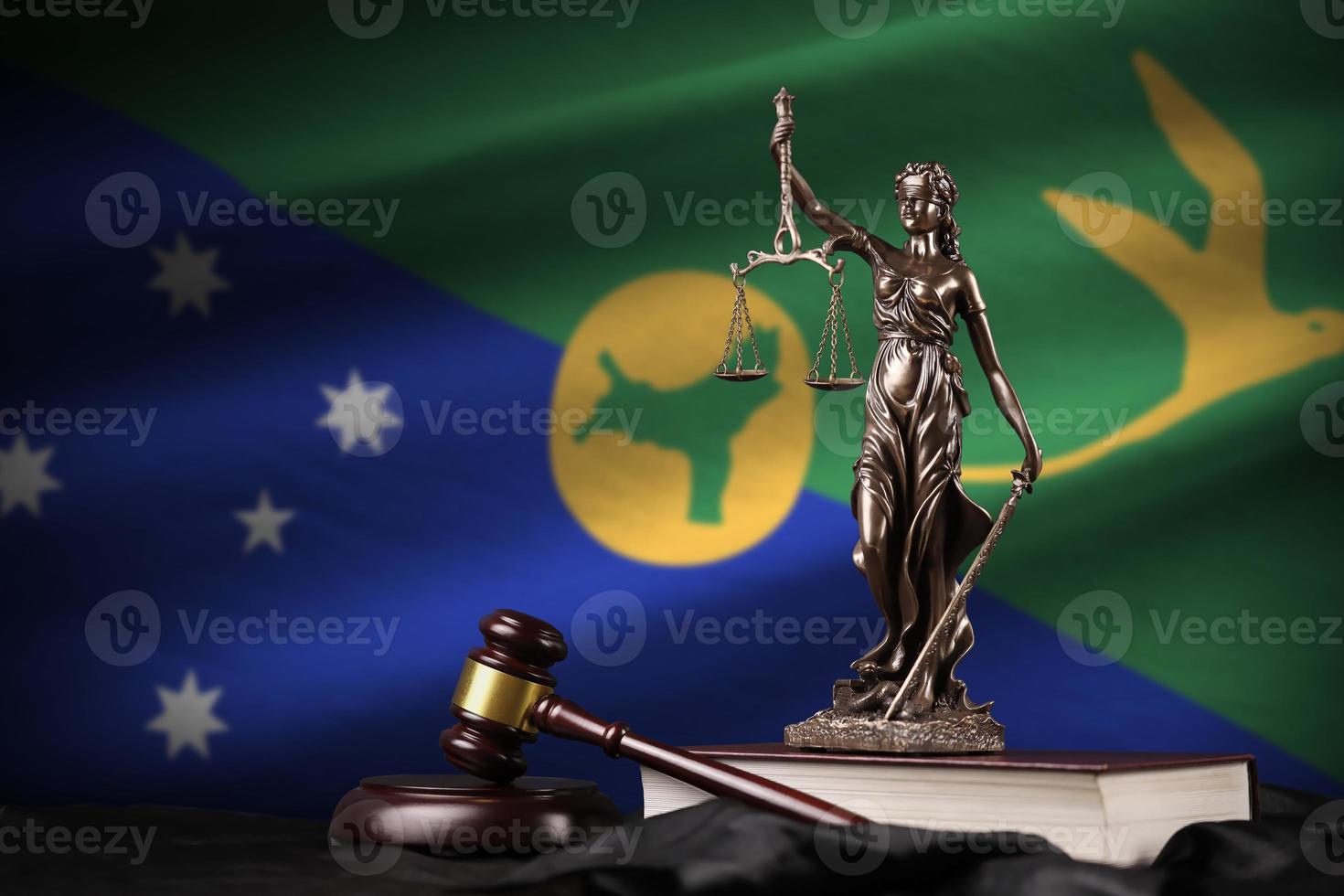 bandeira da ilha de natal com a estátua da senhora justiça, constituição e juiz martelo na cortina preta. conceito de julgamento e culpa foto