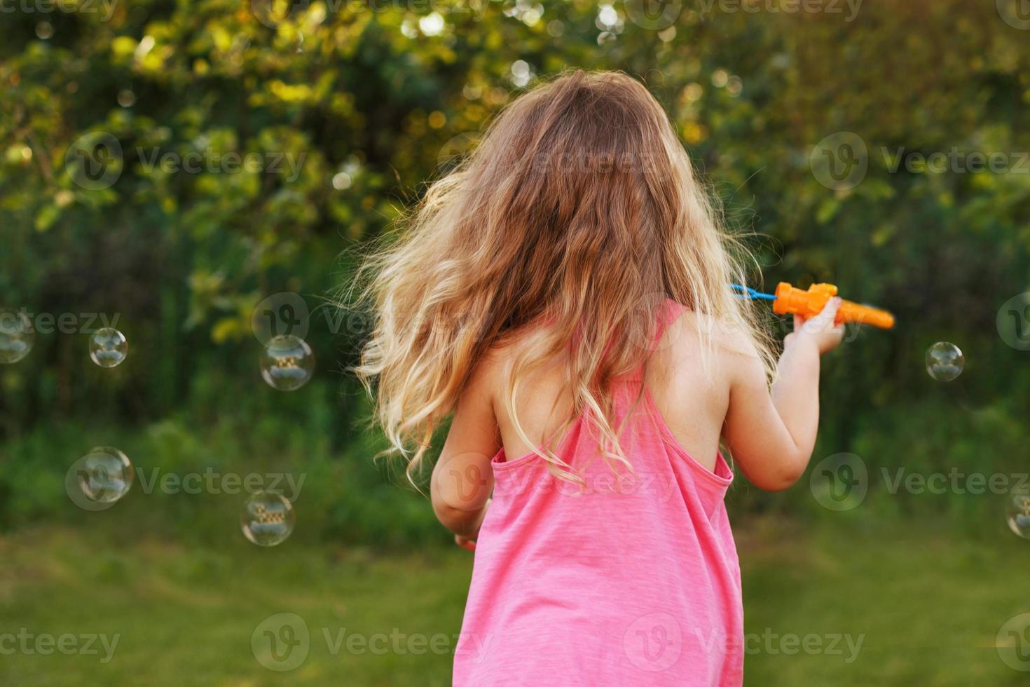 menina bonitinha está soprando bolhas de sabão foto