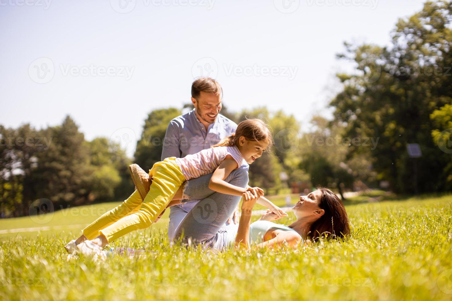 família jovem e feliz com a filhinha se divertindo no parque em um dia ensolarado foto