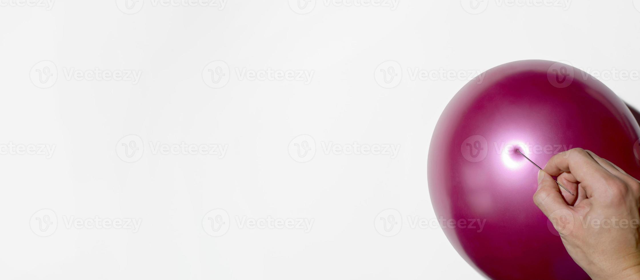 mão masculina perfurando um balão com uma agulha. banner, espaço vazio para texto foto